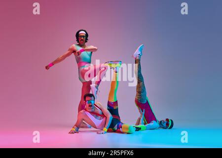 Athletic, funny men in retro colorful sportswear training, doing exercises against gradient blue pink studio background in neon light Stock Photo