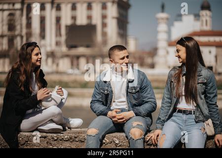 Close up of three friends smiling and enjoying the sun out side while sitting Stock Photo