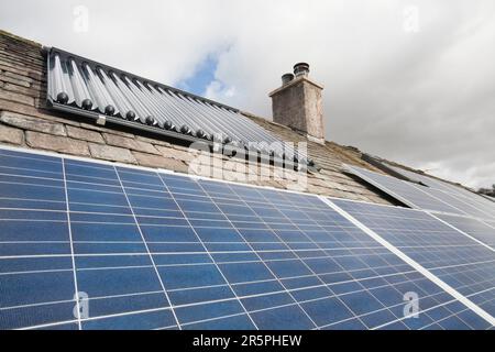Solar voltaic electricity generating panels and solar hot water panels on a house roof in Ambleside, Cumbria, UK. This array provides all the hot water and the electricity for the Stock Photo