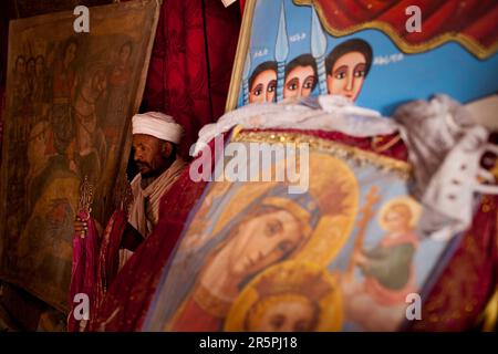 An Ethiopian Orthodox priest stands amidst ancient religious paintings in Bet Giyorgis, Lalibela, Northern Ethiopia. Stock Photo