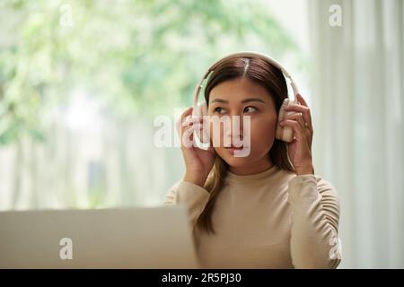 Portrait of young woman listening to music or podcast in headphones Stock Photo