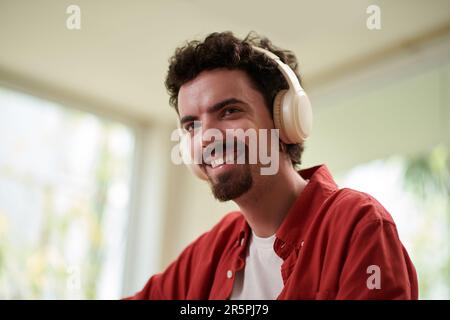 Portrait of joyful developer listening to music when working from home Stock Photo