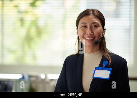 Portrait of positive businesswoman with empty badge on jacket smiling at camera Stock Photo