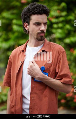 Portrait of developer with curly hair standing outdoors and looking away Stock Photo