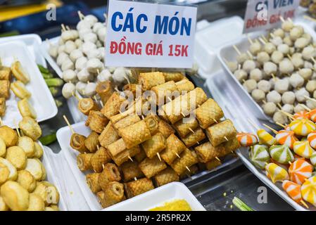 Many snacks and seafood in vietnamese night market in food festival, sign 'meat rolls, price 15 000 dongs' Stock Photo