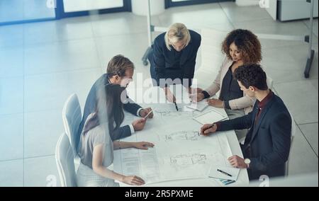 Strategizing their way to stellar designs. a team of corporate architects collaborating on a plan in a modern office. Stock Photo