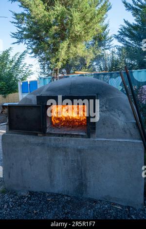 A wood fire burning in a traditional oven for cooking meat at the restaurant at the La Azul WInery, Tupungato, Argentina.  Once the fire has burned do Stock Photo
