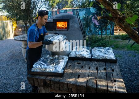 A chef prepares trays of meat to bake in a traditional wood-fired oven at the restaurant of the La Azul WInery, Tupungato, Argentina. Stock Photo