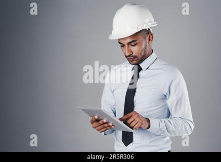 Planning for every eventuality. a well-dressed civil engineer using his tablet while standing in the studio. Stock Photo