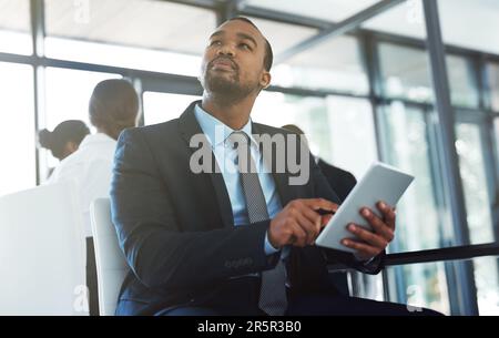 Using smart technology to make smart business decisions. a thoughtful young businessman using a digital tablet during a meeting at work. Stock Photo