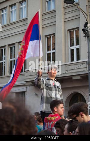 A boy waving a Serbian flag at a protest in Belgrade where the gathered citizens express their disagreement with the current government's policy. Stock Photo