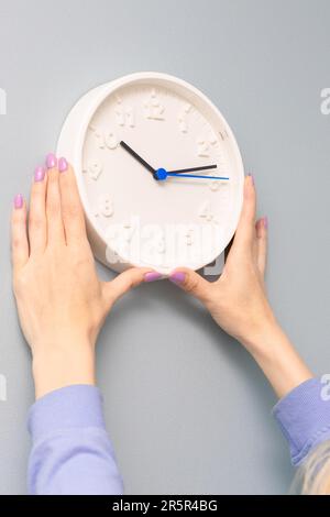 woman hangs a clock on the wall of the room. woman hangs a clock on the wall. Stock Photo
