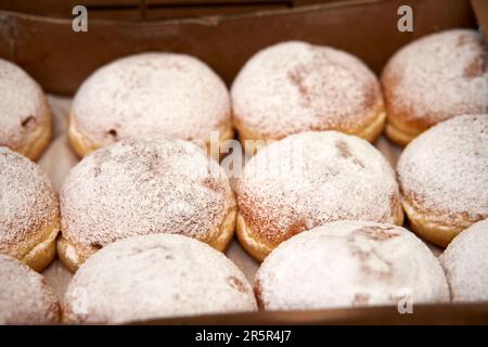 A close-up image of several donuts stacked in a colorful box Stock Photo