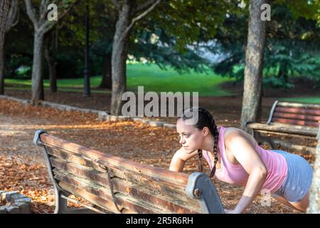 A mature woman exercising outdoors on a park bench Stock Photo