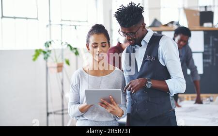 Together with technology, were unbeatable. two businesspeople working together on a digital tablet in an office. Stock Photo