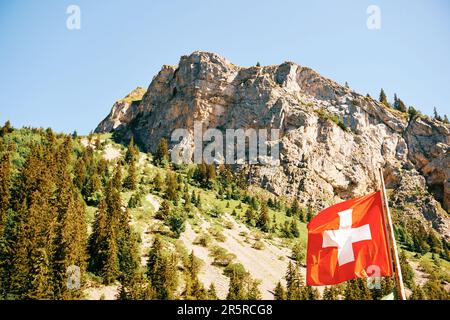 Swiss flag flies against the background of Alpine mountains Stock Photo