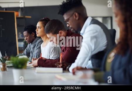 Engaged in an informative seminar. a group of businesspeople listening to a presentation in an office. Stock Photo