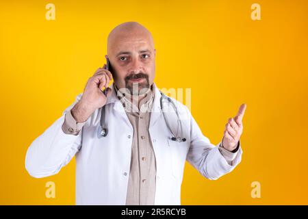 middle aged caucasian angry doctor on the phone. Portrait of middle aged physician with raised hand holding smartphone looking camera annoyed concept Stock Photo