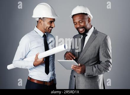 Their partnership is built on a solid foundation. two civil engineers discussing building plans while standing in the studio. Stock Photo