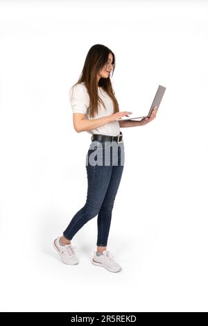 Using laptop, full length body size side view of woman using laptop. Teen, attractive girl holding notebook in hands browsing internet. Stock Photo