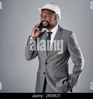 Working hard and loving it. a well-dressed civil engineer using his cellphone while standing in the studio. Stock Photo