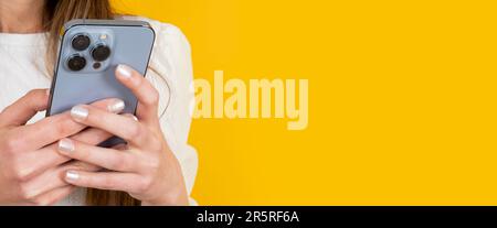 Woman holding smartphone. Modern mobile phone with three cameras in lady's hand. Typing message, messaging, chatting, browsing internet, social media. Stock Photo