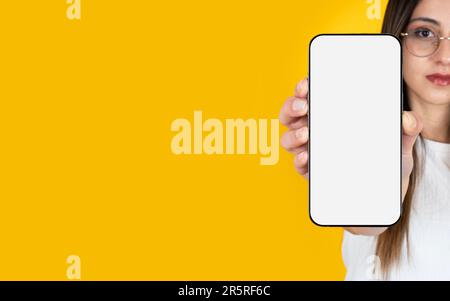 Application advertising banner design concept idea. Young caucasian long brown haired woman showing empty blank screen modern smartphone mockup. Stock Photo