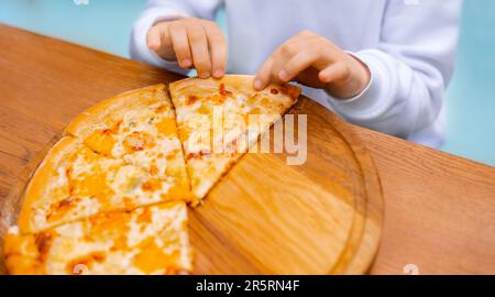 close up child hands holding slice of pizza. girl eat tasty pizza with appetite Stock Photo