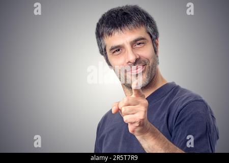 Smiling middle-aged man pointing with index finger over gray background. Success concept. Stock Photo