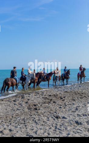 Policoro, Italy - 7 May 2023: People riding horses in a Policoro beach, Basilicata, southern Italy. Stock Photo