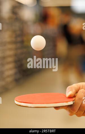 a ball in flight over a table tennis racket in the player's hand Stock Photo