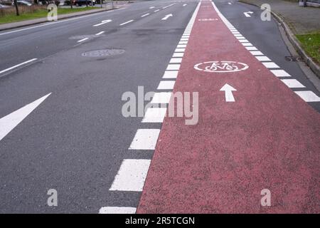 A close-up of a brightly painted bike lane on a city street, with a white arrow pointing in the direction of travel Stock Photo
