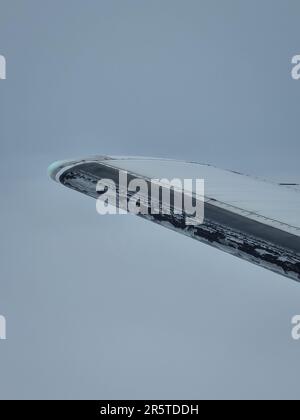 A small airplane is seen soaring through a wispy, hazy sky, viewed from a lower angle Stock Photo