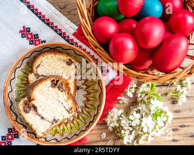 A top view of painted Easter eggs and Cozonac slices on a kitchen table Stock Photo