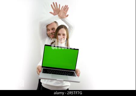 businessman sitting at a table holding a a tablet over his head business woman with blonde hair sitting next to a tablet and points to hand, eye winks. High quality photo Stock Photo