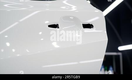Installing a protective film on the car paintwork. Professional installation of a protective film on a car body. Car wrapping with vinyl film or film Stock Photo
