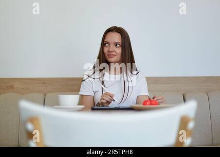 Pretty female drawing a sketch on a tablet pc with a stylus pen in a cafe. Beautiful young woman using a portable computer to draw an illustration Stock Photo