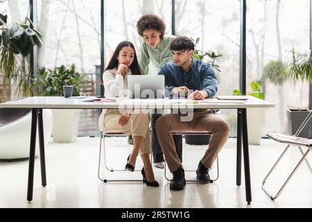 Team Of Coworkers Looking At Laptop Having Issue In Office Stock Photo