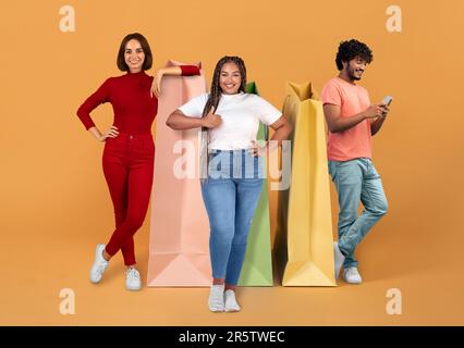 Happy multicultural millennials posing next to huge shopping bags, collage Stock Photo