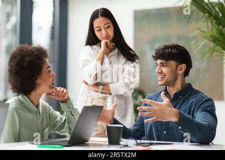 Colleagues Talking Sitting At Laptops During Work Meeting In Office Stock Photo