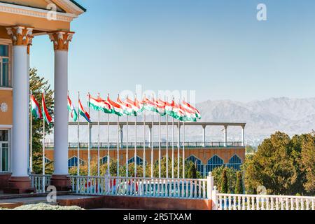 Khujand, Tajikistan - October 17, 2019: View with Waving Tajikistan Flags by the Arbob Cultural Palace in a sunny blue sky day Stock Photo