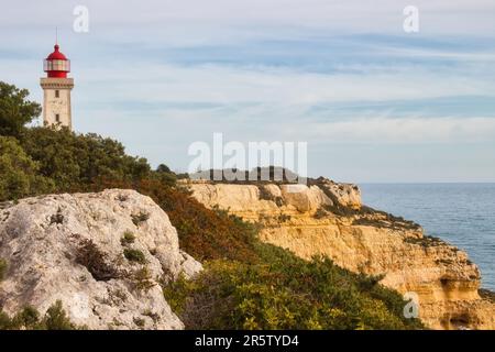 Carvoeiro, Portugal - December 25, 2019: Top of Farol De Alfanzina Lighthouse one a cliff behing green shrubs next to the Atlantic ocean on a sunny wi Stock Photo