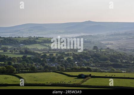 Morning light shines on the farmland and woods of the Lydford and North Brentor valleys under the hills and tors of Dartmoor in West Devon. Stock Photo