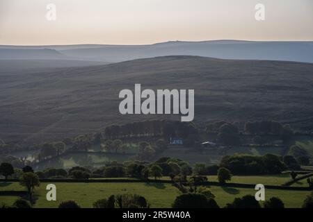 Morning light shines on Gibbet Hill and the distant hills of the Willsworthy Range in Dartmoor as seen from Brent Tor hill in West Devon. Stock Photo