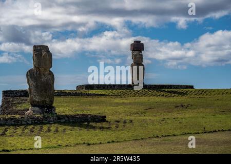A photo of two Moai statues facing inward on Easter Island, one with eyes clearly visible. Stock Photo