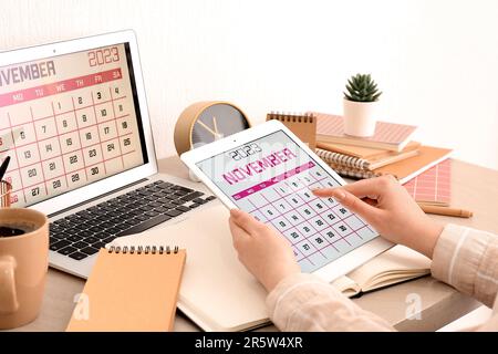 Woman holding tablet computer with calendar at workplace Stock Photo