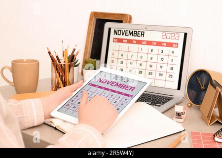 Woman holding tablet computer with calendar at workplace Stock Photo