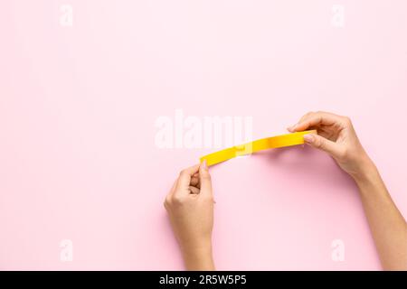 Female hands holding adhesive tape roll on pink background Stock Photo