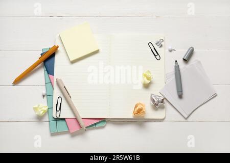 Sticky notes with different stationery supplies on white wooden background Stock Photo