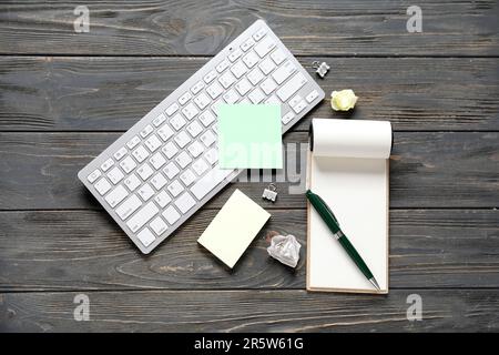 Sticky notes with keyboard and notebook on black wooden background Stock Photo